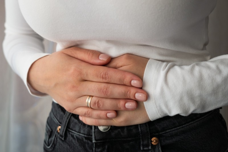 Femeie care se tine de burta, simptom al premenopauzei