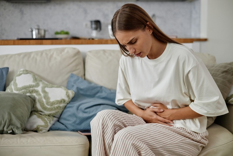  Femeie care se tine de burta, simptom al premenopauzei 
